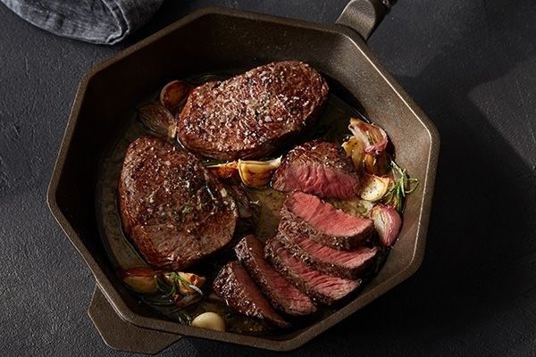 Seared steaks with browned crust in a cast-iron pan