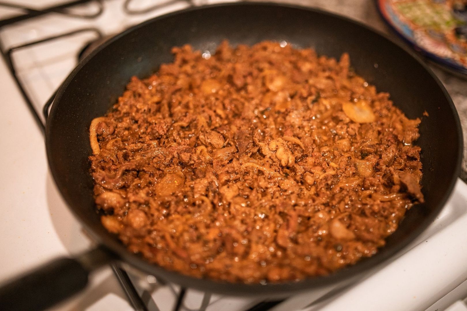 Browned ground meat and onions cooking in a black skillet