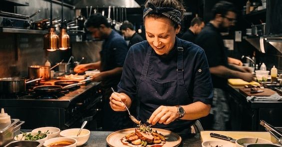 Chef plating a dish on a busy commercial kitchen service line